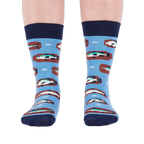 Person standing forward wearing light blue crew socks with fish and knot patterns on a white background.
