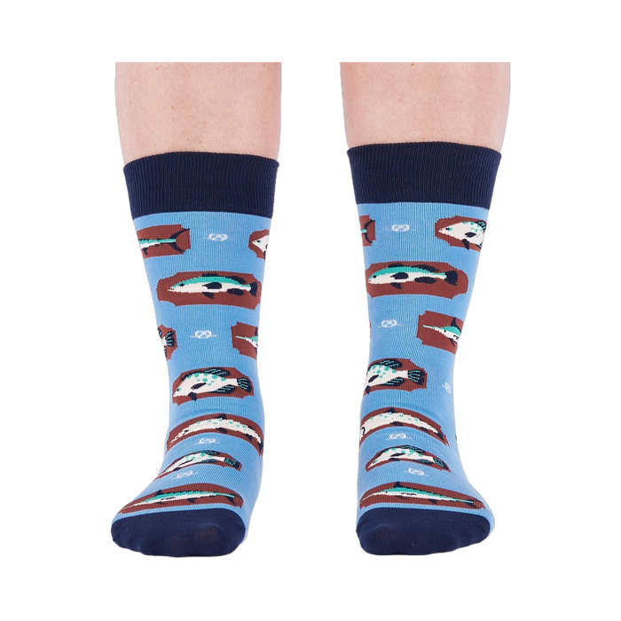 Person standing forward wearing light blue crew socks with fish and knot patterns on a white background.