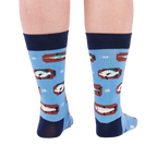 Person standing backward, showing the heels of light blue crew socks with fish and knot patterns on a white background.