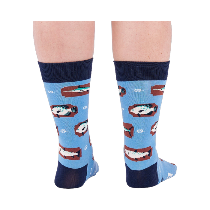 Person standing backward, showing the heels of light blue crew socks with fish and knot patterns on a white background.