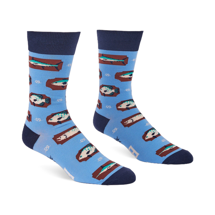 Pair of light blue crew socks with a repeating pattern of fish on brown rectangular shapes and white knot designs.