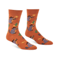 A pair of burnt orange crew socks with cartoon raccoons in cowboy hats lassoing, green cacti, yellow suns, and lizards.