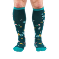 Front view of legs wearing dark teal knee-high socks with turquoise cuffs, showing scattered masks, roses, and musical notes.