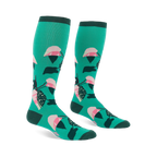 Pair of knee-high teal socks with a repeating philodendron leaf pattern in pink, white, dark green, and black. Dark green cuffs, heels, and toes.