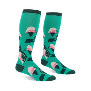 Pair of knee-high teal socks with a repeating philodendron leaf pattern in pink, white, dark green, and black. Dark green cuffs, heels, and toes.