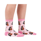 A person's lower legs wearing the light pink musical cat crew socks, shown from the side against a white background.