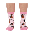 A person's lower legs wearing the light pink musical cat crew socks, shown from the front against a white background.