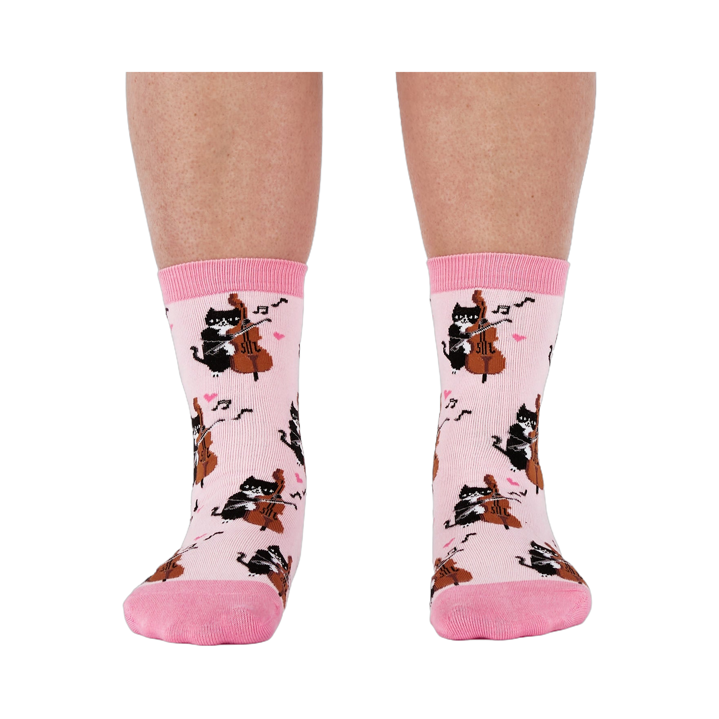 A person's lower legs wearing the light pink musical cat crew socks, shown from the front against a white background.