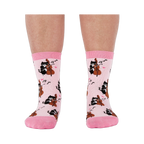 A person's lower legs wearing the light pink musical cat crew socks, shown from the front against a white background.