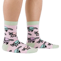 Side view of a person wearing pink crew socks with a pattern of raccoons and pastel macarons, showing light green cuffs and heels.