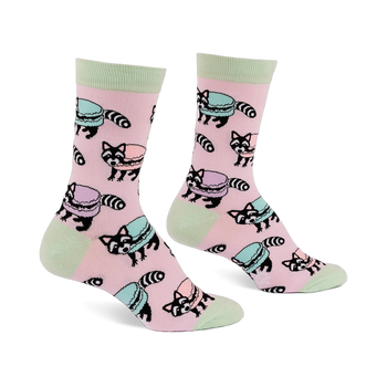 Pair of pink crew socks with light green accents, featuring a repeating pattern of cartoon raccoons and pastel macarons.