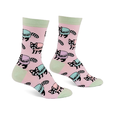 Pair of pink crew socks with light green accents, featuring a repeating pattern of cartoon raccoons and pastel macarons.