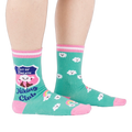 A person's legs wearing teal 'Hiking Club' crew socks, posed on a white background. Left sock shows shield design.