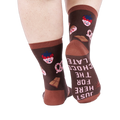 View from behind of person wearing chocolate pattern socks. The sole of one sock says "JUST HERE FOR THE CHOCOLATE".