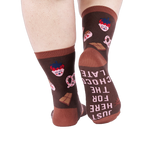 View from behind of person wearing chocolate pattern socks. The sole of one sock says "JUST HERE FOR THE CHOCOLATE".