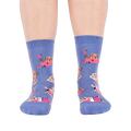 Person's feet wearing periwinkle crew socks with a guinea pig workout pattern, viewed from the front on white.