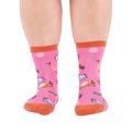 Front view of someone's lower legs wearing pink socks with colorful jelly candy snails, candy swirls, and an orange cuff.