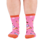 Front view of someone's lower legs wearing pink socks with colorful jelly candy snails, candy swirls, and an orange cuff.
