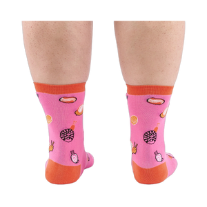 Back view of someone's calves wearing pink socks with jelly candy snails, candy swirls, and contrasting orange heels.