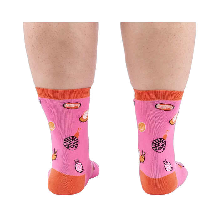 Back view of someone's calves wearing pink socks with jelly candy snails, candy swirls, and contrasting orange heels.