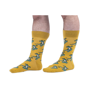 Someone wearing yellow crew socks with a green skateboarding alligator pattern, set against a black background.
