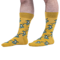 Someone wearing yellow crew socks with a green skateboarding alligator pattern, set against a black background.