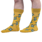 Someone wearing yellow crew socks with a green skateboarding alligator pattern, set against a black background.