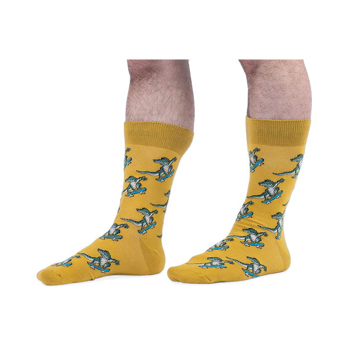 Someone wearing yellow crew socks with a green skateboarding alligator pattern, set against a black background.