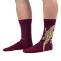 A person wearing burgundy crew socks with a large tan and yellow bearded dragon printed on the outer side of the leg.