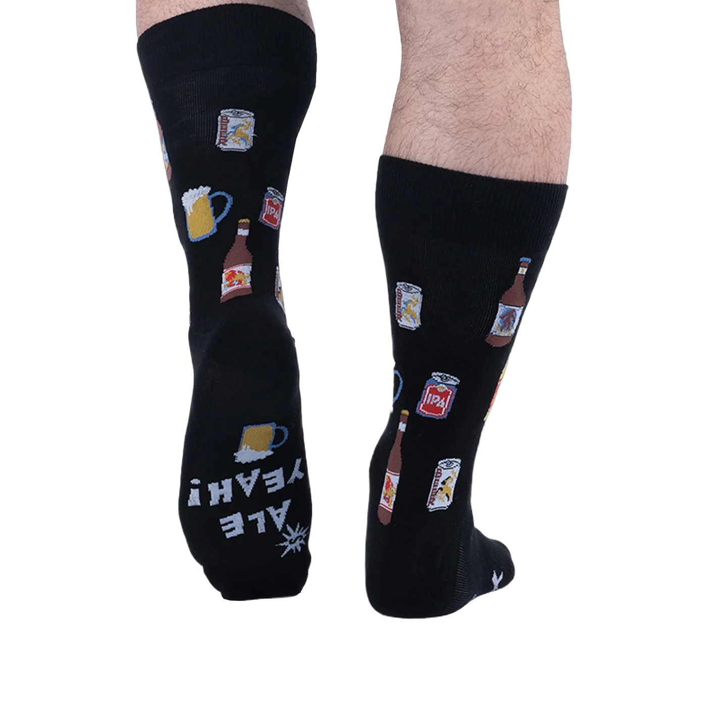 Back view of someone wearing black beer pattern socks, showing the sole of the left foot with white text reading ALE YEAH!