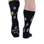 Back view of someone wearing black beer pattern socks, showing the sole of the left foot with white text reading ALE YEAH!
