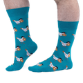 Person with hairy legs wearing bright teal crew socks that feature a pattern of white chickens carrying buttered waffles.