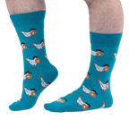 Person with hairy legs wearing bright teal crew socks that feature a pattern of white chickens carrying buttered waffles.