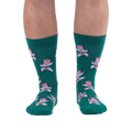 Front view of a person's lower legs wearing green socks with a pattern of pink pigs in white karate uniforms.