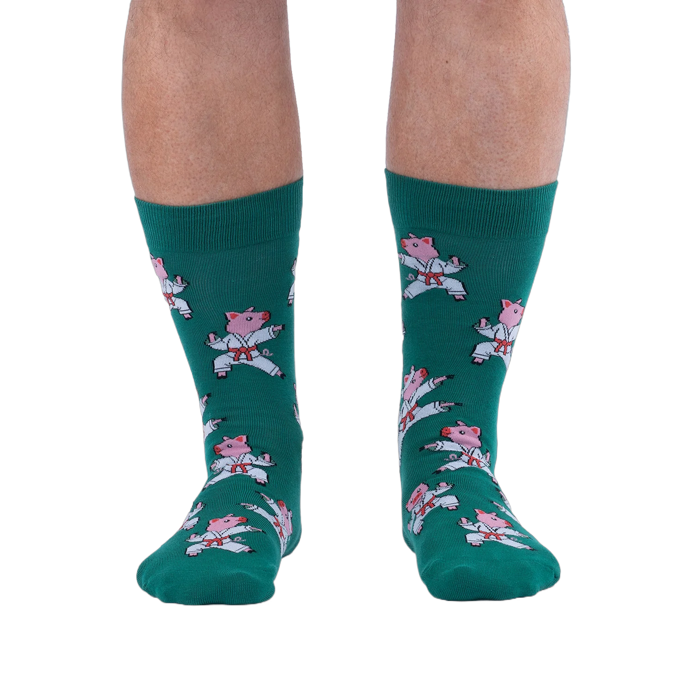 Front view of a person's lower legs wearing green socks with a pattern of pink pigs in white karate uniforms.