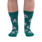 Front view of a person's lower legs wearing green socks with a pattern of pink pigs in white karate uniforms.
