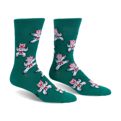 Pair of green crew socks featuring a pattern of pink pigs wearing white karate uniforms and red belts in martial arts poses.