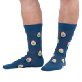 Lifestyle shot of a person wearing dark blue crew socks with a deviled egg pattern against a solid black background.