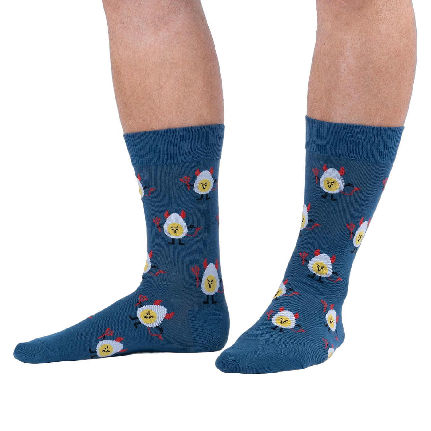 Lifestyle shot of a person wearing dark blue crew socks with a deviled egg pattern against a solid black background.