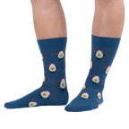 Lifestyle shot of a person wearing dark blue crew socks with a deviled egg pattern against a solid black background.