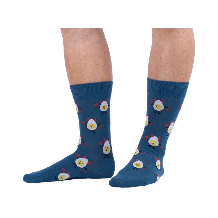 Lifestyle shot of a person wearing dark blue crew socks with a deviled egg pattern against a solid black background.