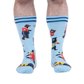 Front view of light blue socks on a person, showing a panda in a red jersey kicking a soccer ball among other playing bears.