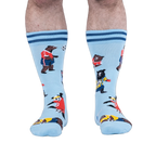 Front view of light blue socks on a person, showing a panda in a red jersey kicking a soccer ball among other playing bears.