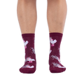 Front view of someone wearing burgundy crew socks with a disco ball and cowboy chicken pattern against a black background.