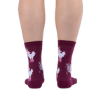 Back view of legs wearing burgundy crew socks featuring white chickens in pink boots and disco balls on a black background.