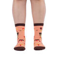 Front view of someone wearing peach mushroom socks on a dark background, showing brown toes and scattered ladybug details.