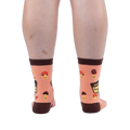 Back view of a person wearing peach mushroom socks, highlighting the dark brown heels, top cuffs, and happy mushroom pattern.