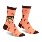 Peach socks with brown trim, featuring cute smiling mushrooms, ladybugs, and a sign reading Having a Fungi Time.