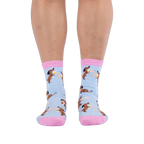 Front view of a person wearing light blue socks with pink cuffs and a pattern of dachshund dogs holding martini glasses.