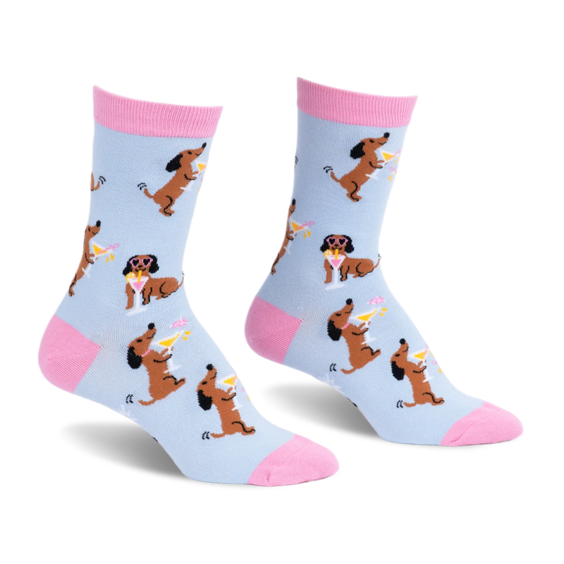 Light blue crew socks with pink accents, featuring a pattern of brown dachshunds holding martinis and wearing sunglasses.
